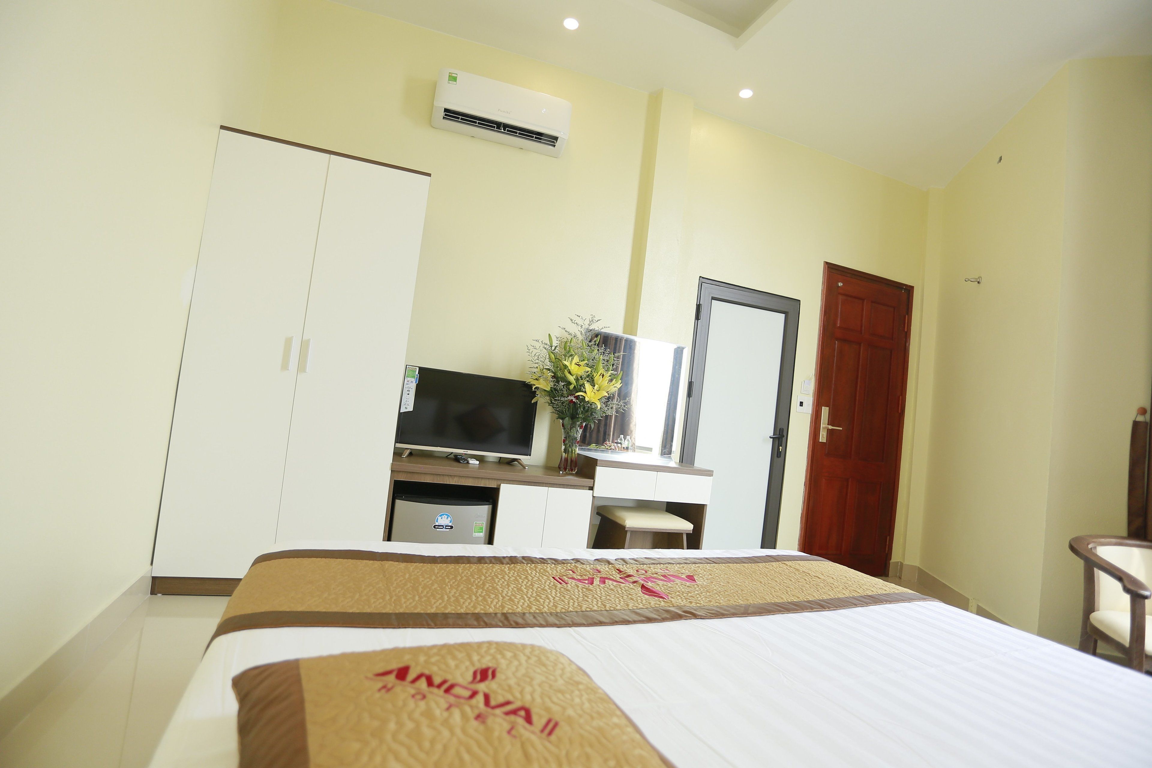 A hotel room with a bed, a TV, a desk, and a wardrobe.