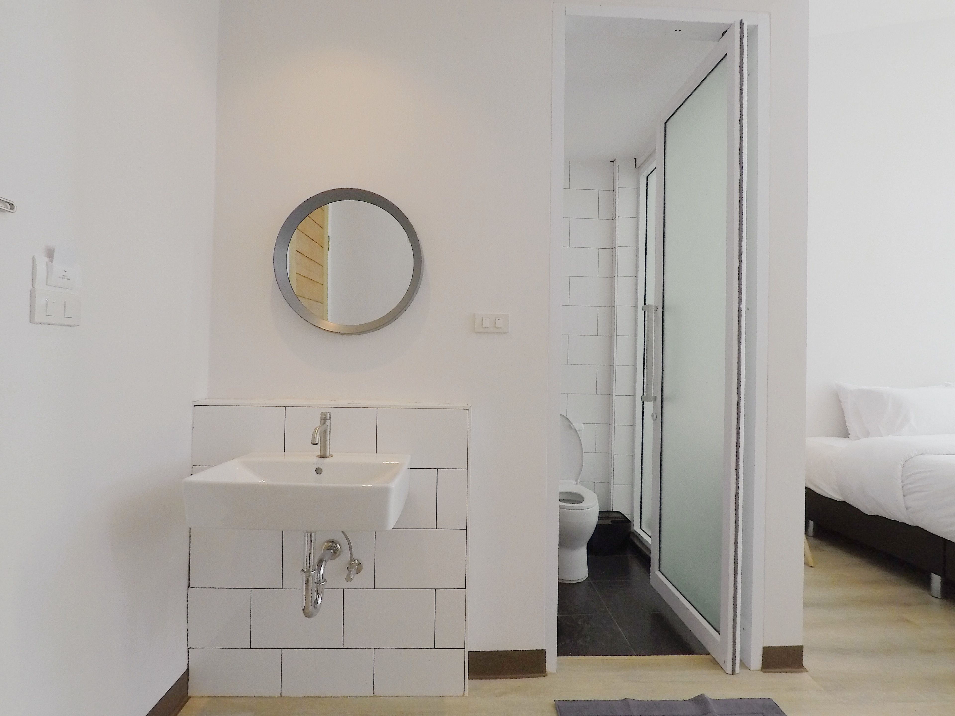 Un baño moderno con lavamanos, espejo e inodoro blancos.