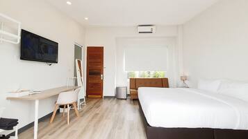A modern hotel room with a bed, desk, chair, TV, and window.
