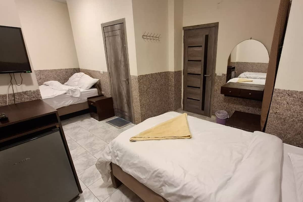 A hotel room with a bed, a desk, a chair, a TV, and a bathroom.