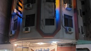 A multi-story building with a central entrance, air conditioning units, and a staircase leading to the entrance.