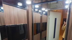 A modern elevator with wooden paneling and glass doors, equipped with overhead lighting.