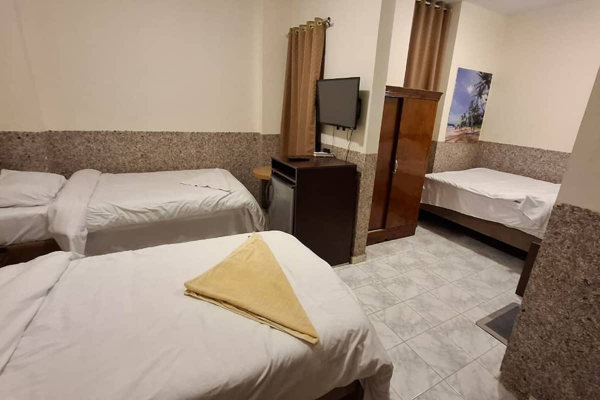A hotel room with two single beds, a small desk with a TV, and a poster on the wall.