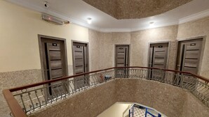 A multi-level interior with a central staircase, metal railings, and doors numbered 105, 106, 107, and 108.