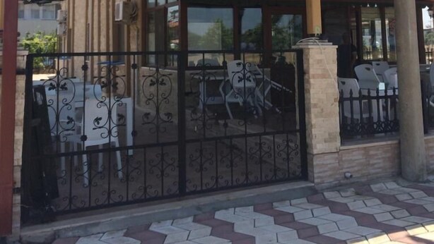 A building with a covered entrance, a flag, and a tiled walkway. - Ev Otel (Çanakkale)