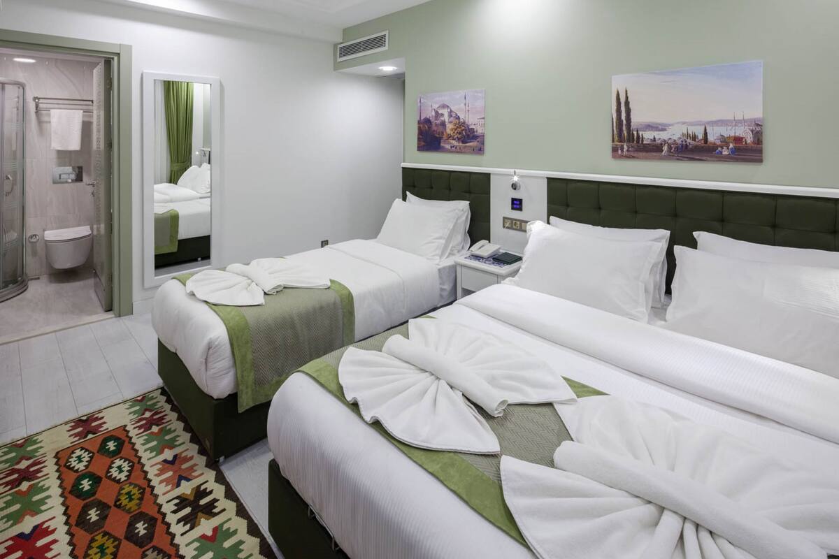 A hotel room with two beds, a bathroom, and a view of the city.