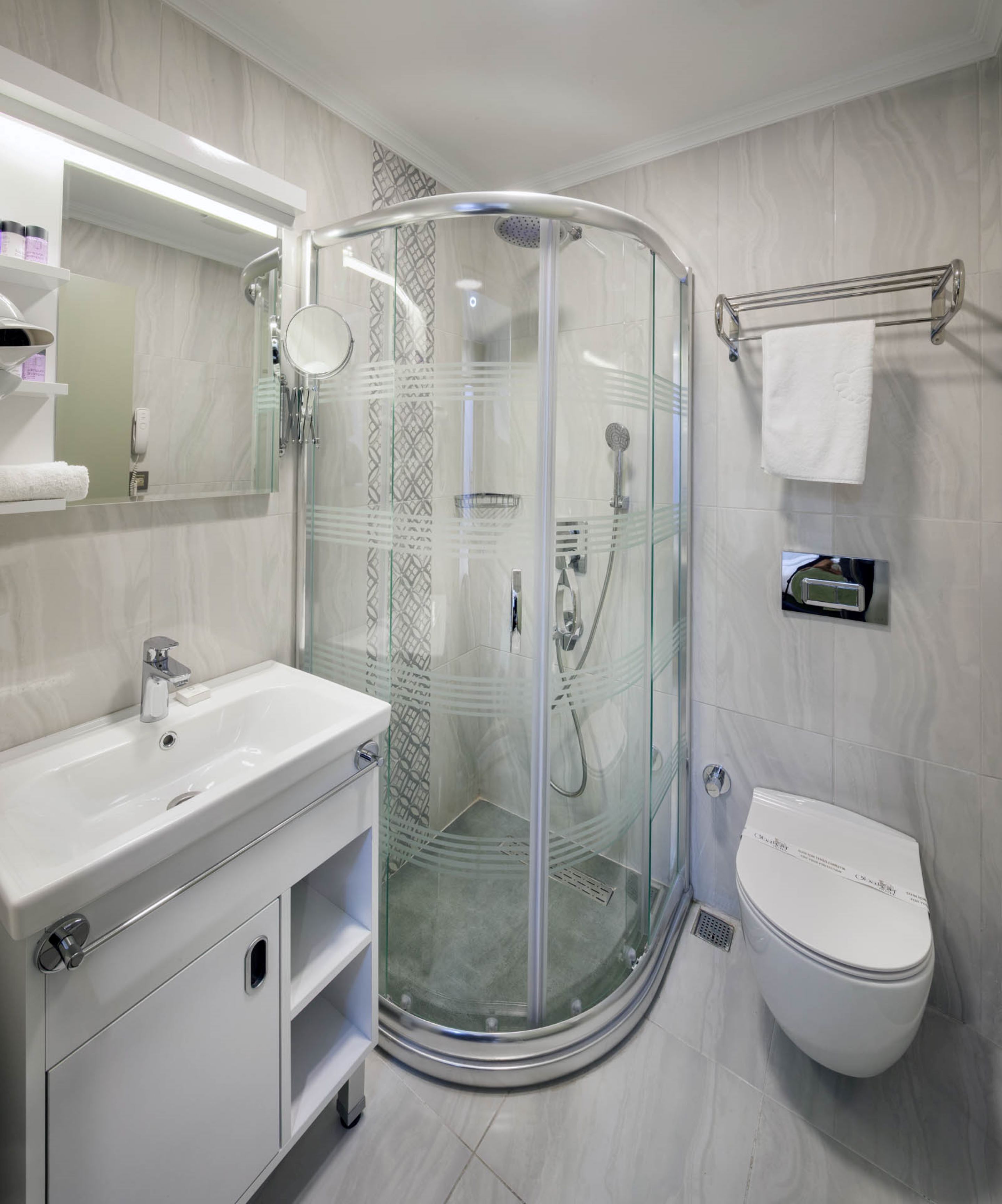 A modern bathroom with a glass-enclosed shower, a white sink, and a toilet.