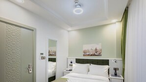 Una habitación de hotel con una cama grande, una mesita de noche, una lámpara y una pintura en la pared.