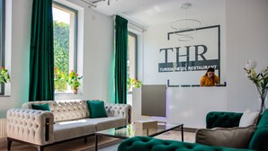 A modern hotel lobby with a sofa, a green armchair, and a reception desk. - Thr center (Curtea De Arges)