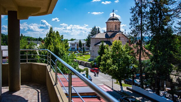 A view from a balcony overlooking a street with a church in the background. - Thr center (Curtea De Arges)
