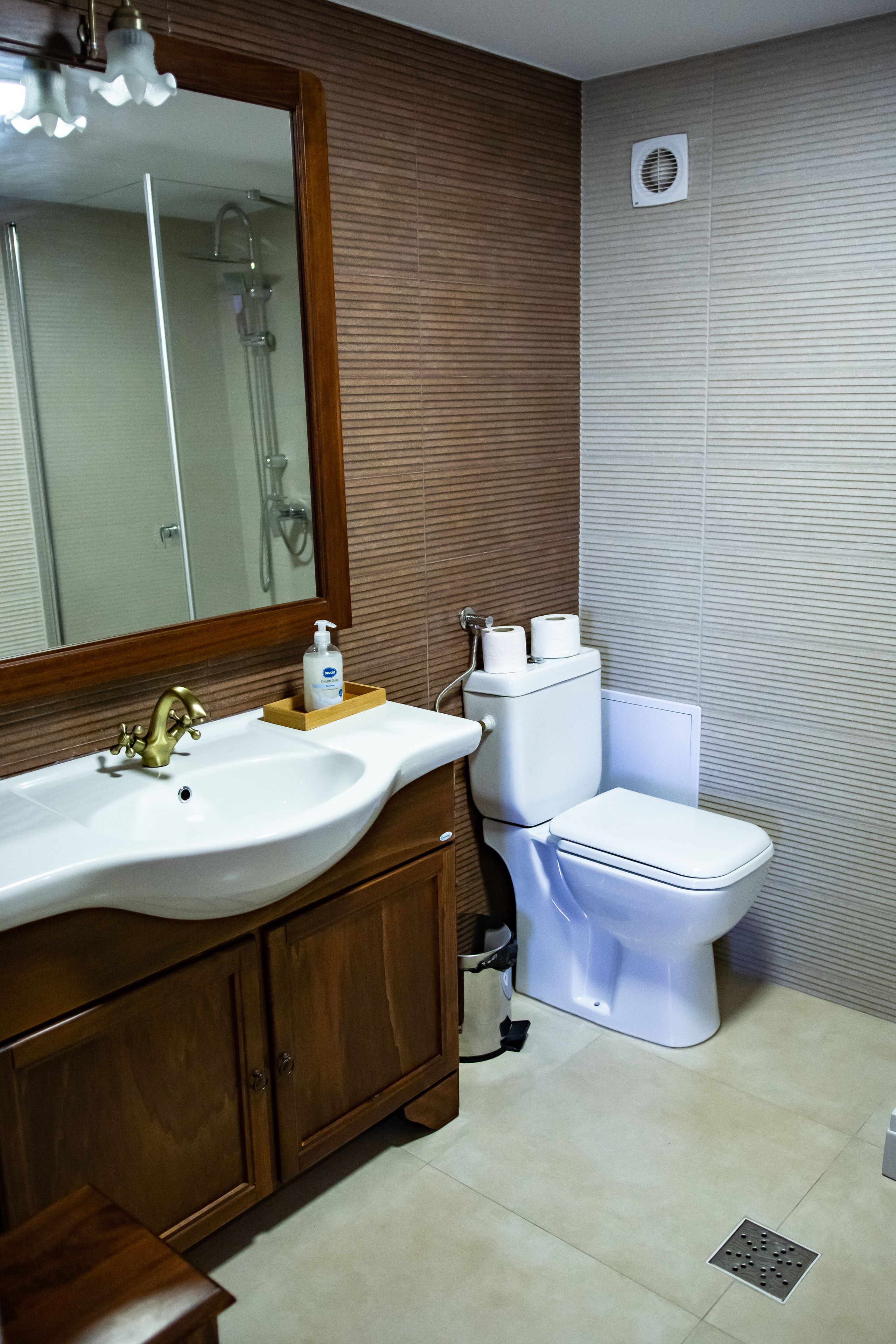 A bathroom with a wooden vanity, a white sink, and a toilet.
