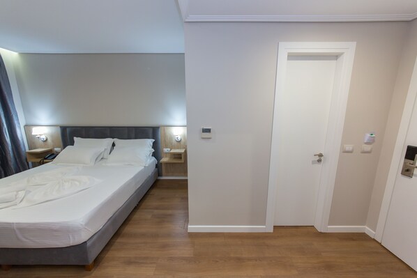 Une chambre d’hôtel avec un lit double, des tables de chevet, une petite table et une porte.