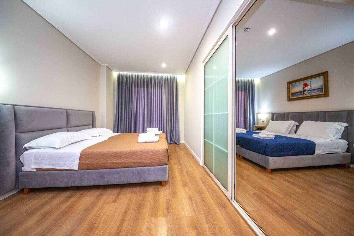 Habitación de hotel con dos camas, suelo de madera y puerta corrediza de cristal.