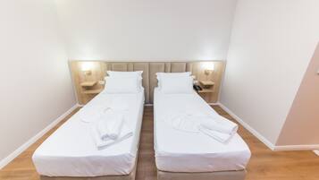 Camera doppia con due letti singoli, ognuno con cuscino, comodino e lampada.