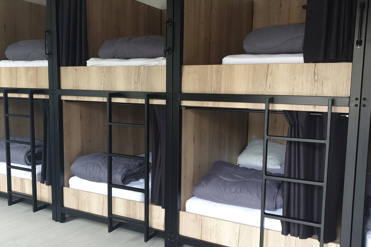 A bunk bed room with wooden frames and black metal railings.