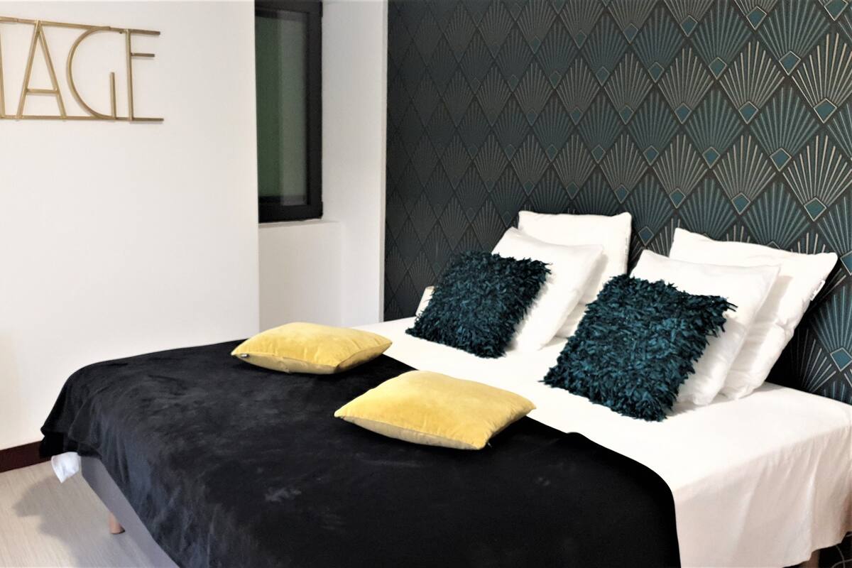 A modern bedroom with a black bedspread, white pillows, and two decorative pillows in yellow and blue.