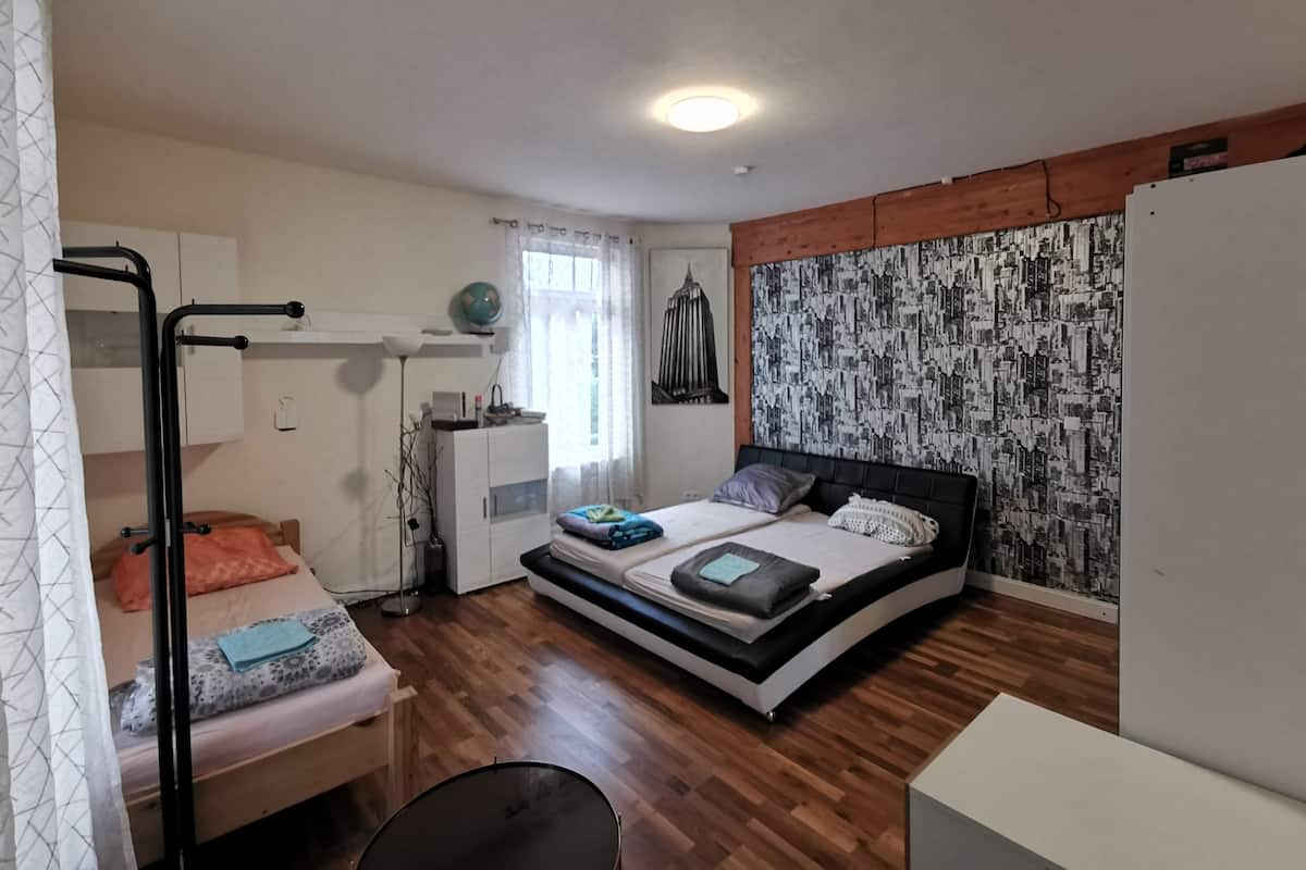 A bedroom with a bunk bed, a desk, a chair, a wardrobe, and a cityscape wall.