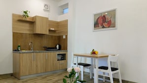 A modern kitchen with wooden cabinets, a sink, and a dining area with two white chairs. - La Maison De Ruby Apartment (Da Nang)