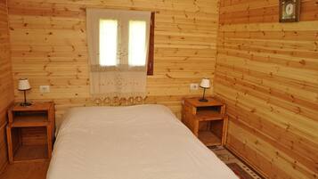 Une chambre rustique en bois, avec un lit, deux tables de chevet, une fenêtre avec des rideaux et une horloge au mur.
