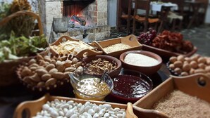 A rustic interior with a stone fireplace, wooden furniture, and various food items displayed on tables. - Farma Sotira (Leskovik)