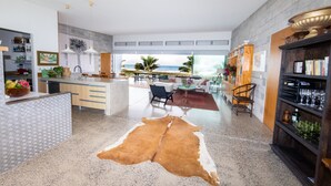 A spacious kitchen with a large island, a dining area with a view of the beach, and a living room with a fireplace. - Coast Cook Islands - 3-Bedroom Beachfront Pool Villa (Rarotonga)