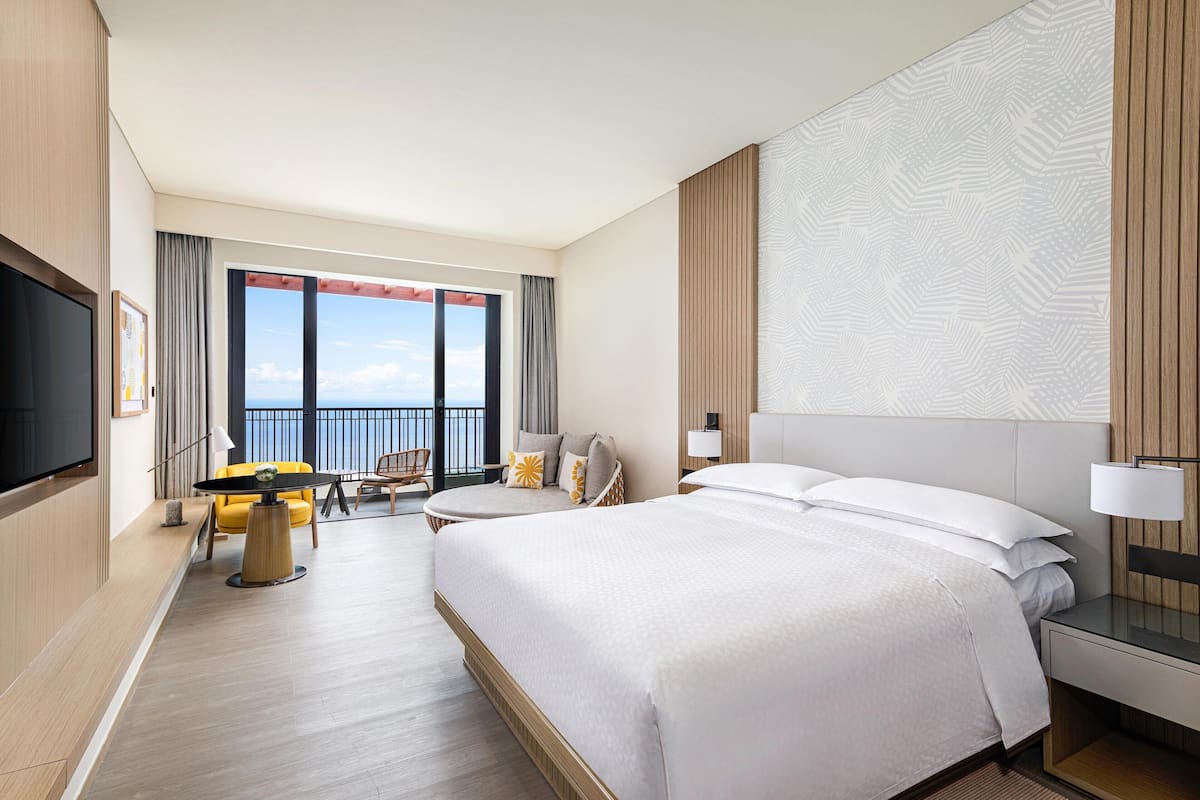 A hotel room with a large bed, a desk, a chair, and a TV.