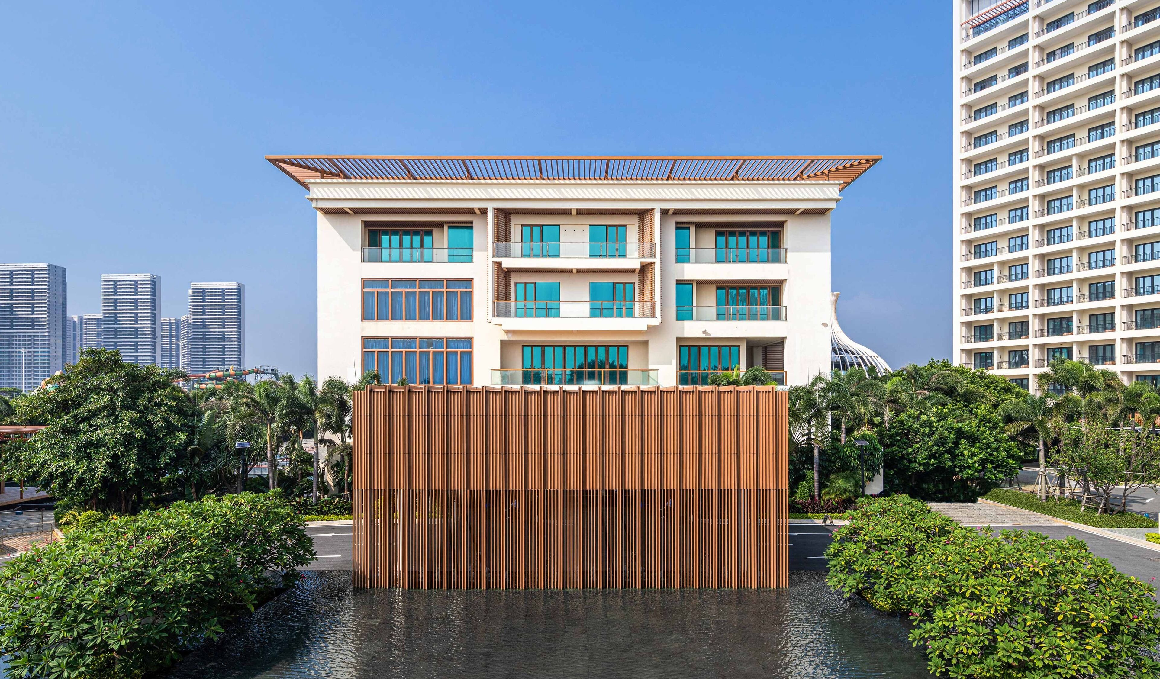 A modern multi-story building with a flat roof, large windows, and a central courtyard with a water feature.