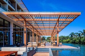 Un área de piscina moderna al aire libre con una pérgola de madera, asientos de descanso y vistas a la piscina.