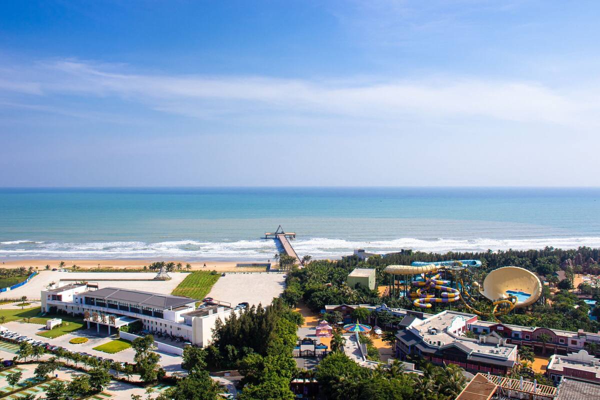 A coastal resort with a beach, water park, and a large building with a parking lot.