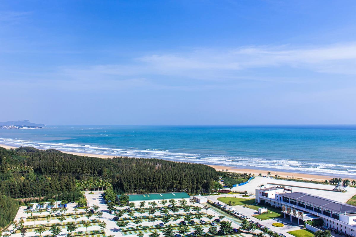 A resort with a beach view, a parking lot, and a building with a green roof.