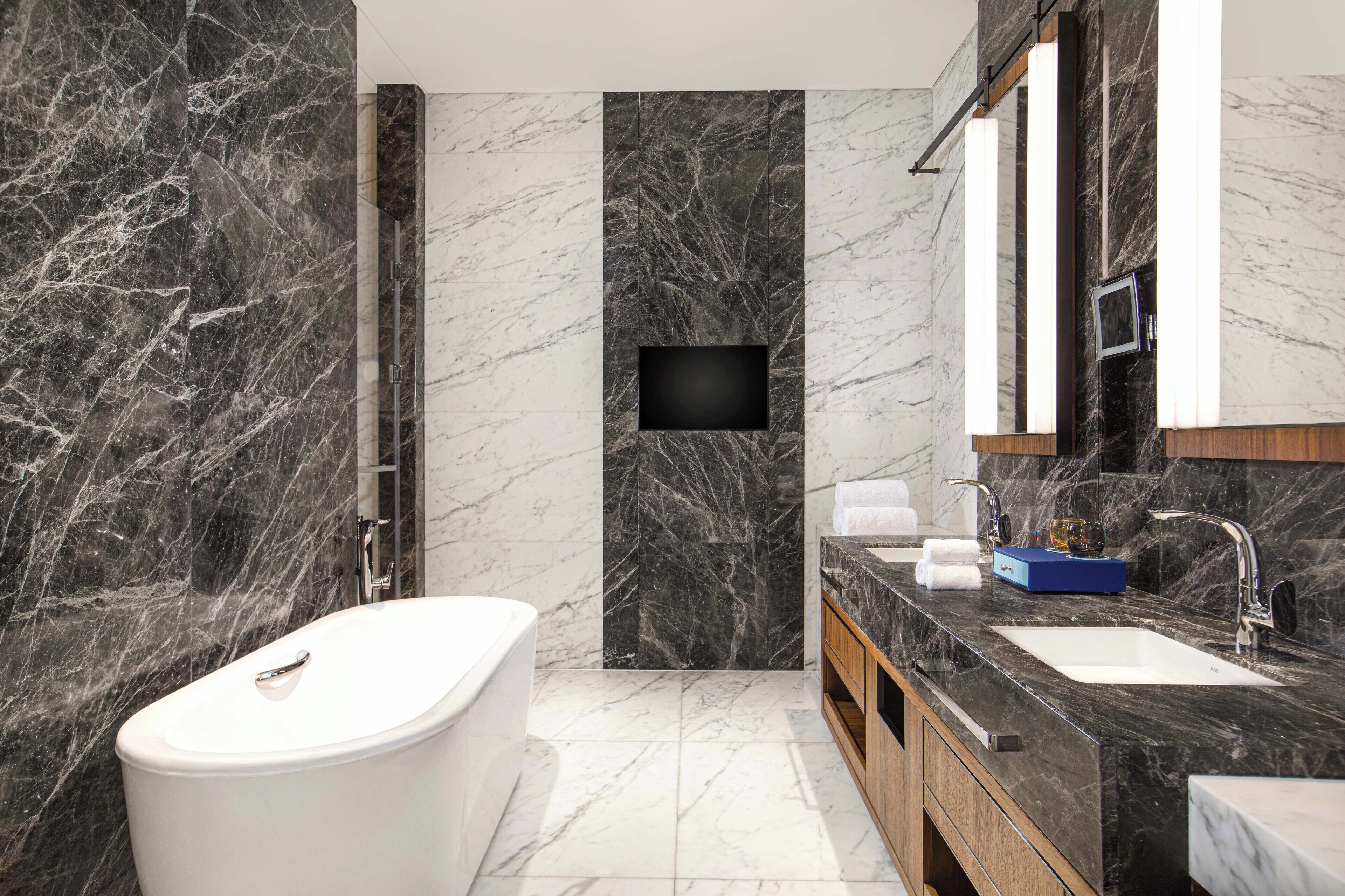 Un bagno moderno con una vasca freestanding, un lavabo con piano in marmo e un ampio specchio sopra il lavabo.