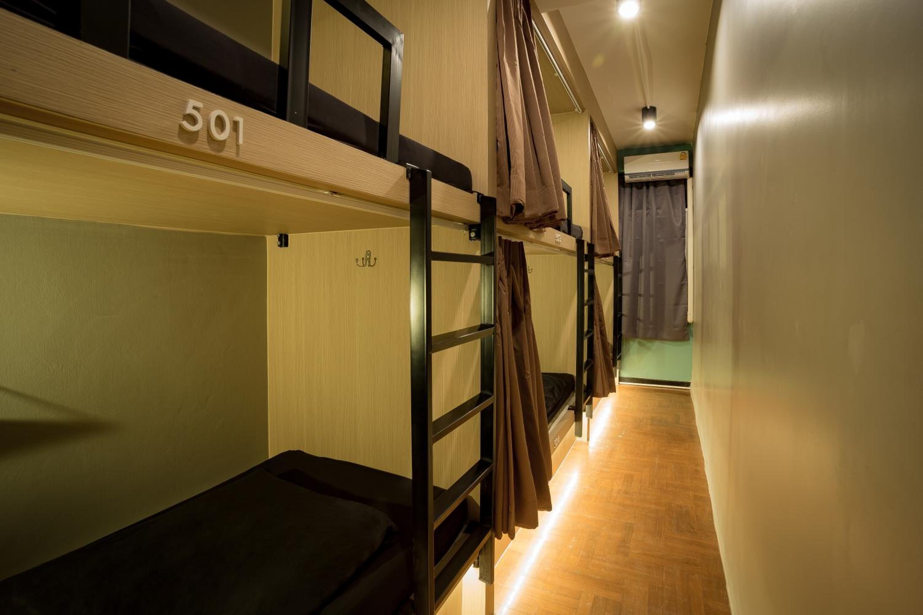 A dormitory room with bunk beds, wooden walls, and a number '501' on the upper bunk.