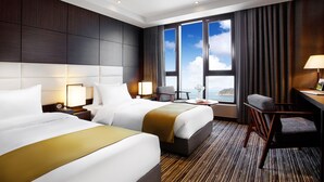 A hotel room with two beds, a desk, a chair, and a view of the sea. - Stellar Hotel (Incheon)