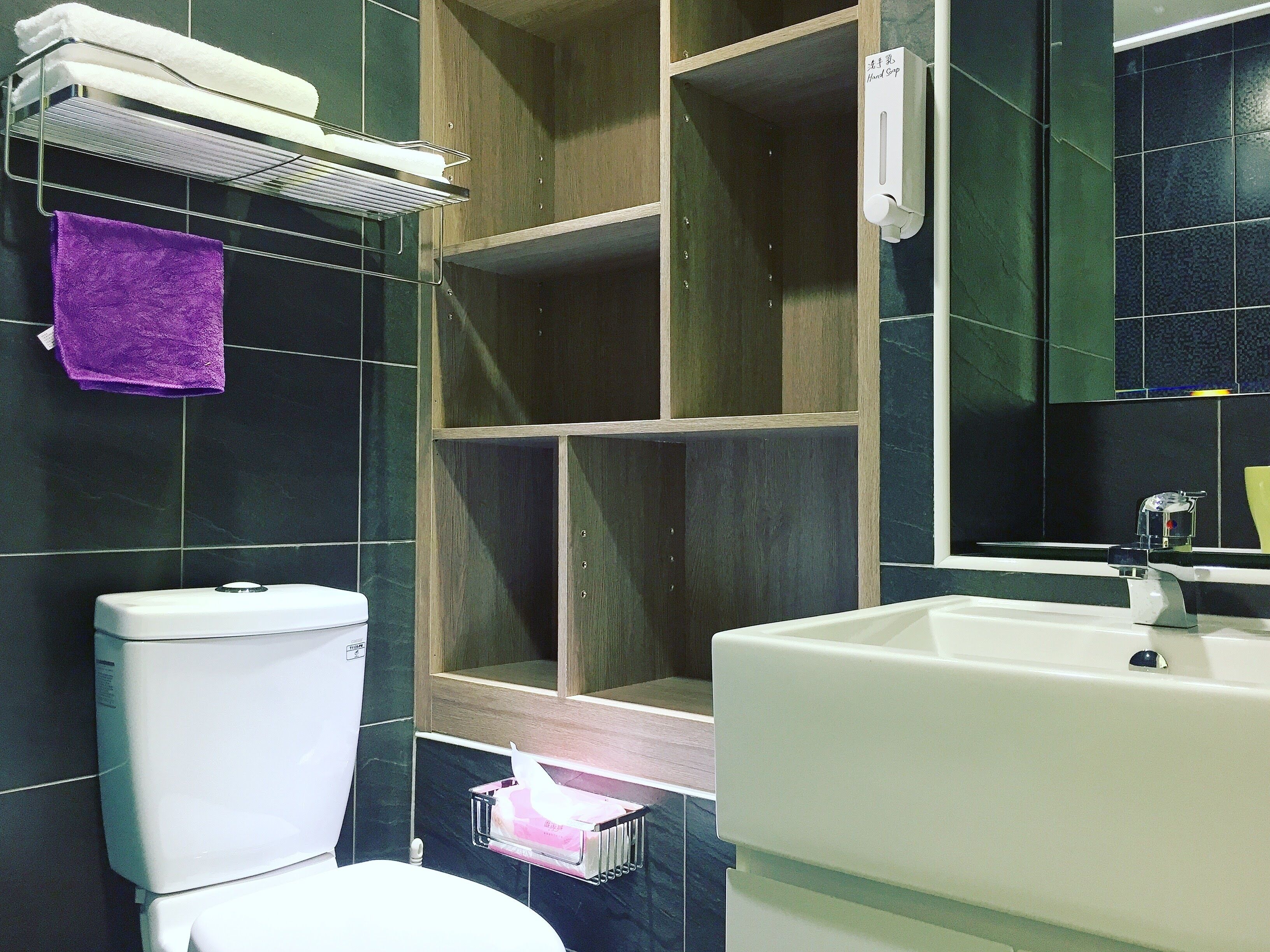 Un baño con inodoro, lavamanos y un perchero con toallas.