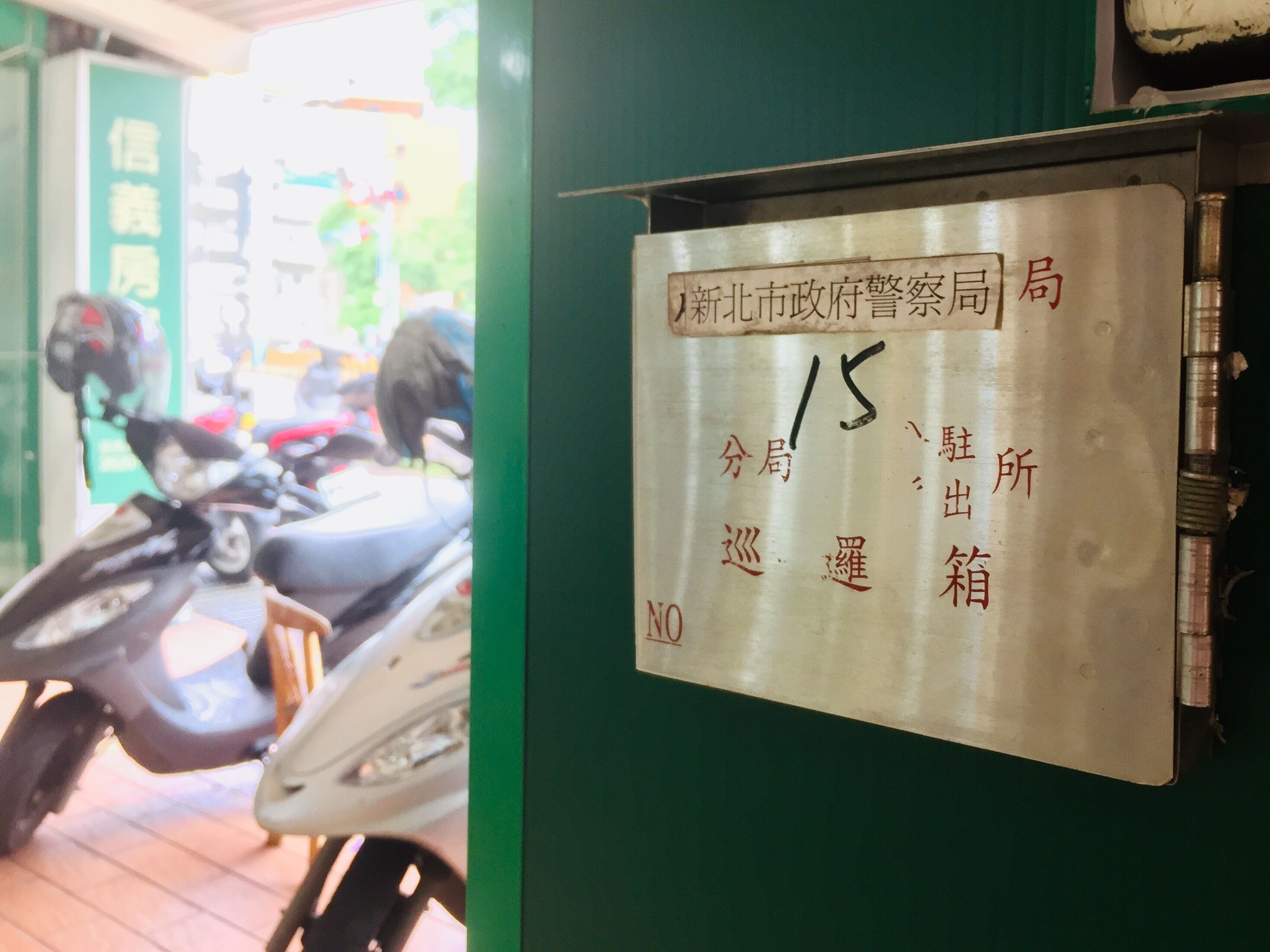 A metal sign with Chinese characters and a number '15' on it, mounted on a green wall.