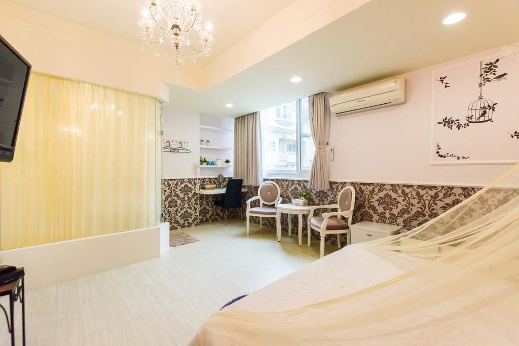 Una habitación de hotel con cama, escritorio, silla, televisión y ventana con cortinas.