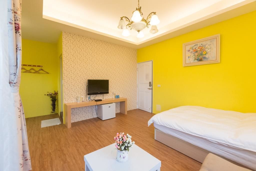 Quarto com cama, televisão, escrivaninha e um pequeno armário.