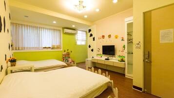 A bedroom with two beds, a desk with a computer, a television, and a door with a notice.