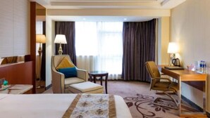 A hotel room with a bed, two armchairs, a small table, a desk, and a window with curtains. - Zhuhai Asian Star Hotel (Zhuhai)
