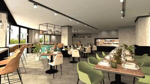 Un intérieur de restaurant moderne avec des tables hautes, des chaises vertes et un espace bar.
