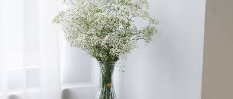 A desk with a vase of flowers, a clipboard, and a chair.
