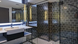Une salle de bain moderne avec un sol carrelé en noir et blanc, une cabine de douche en verre et un grand miroir au-dessus du lavabo.