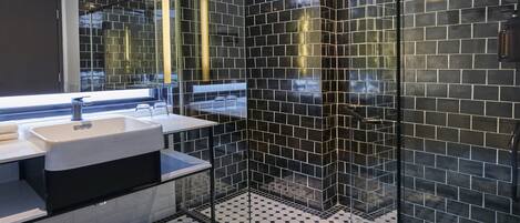 A modern bathroom with a black and white tiled floor, a glass shower enclosure, and a large mirror above the sink.