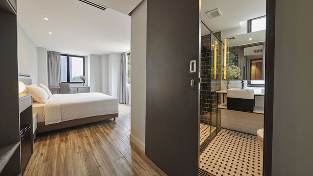 Une chambre d’hôtel moderne dotée d’un grand lit, d’une salle de bain avec une douche en verre et offrant une vue sur la ville.