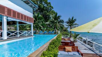 Alberca al aire libre, sombrillas en la alberca y camastros