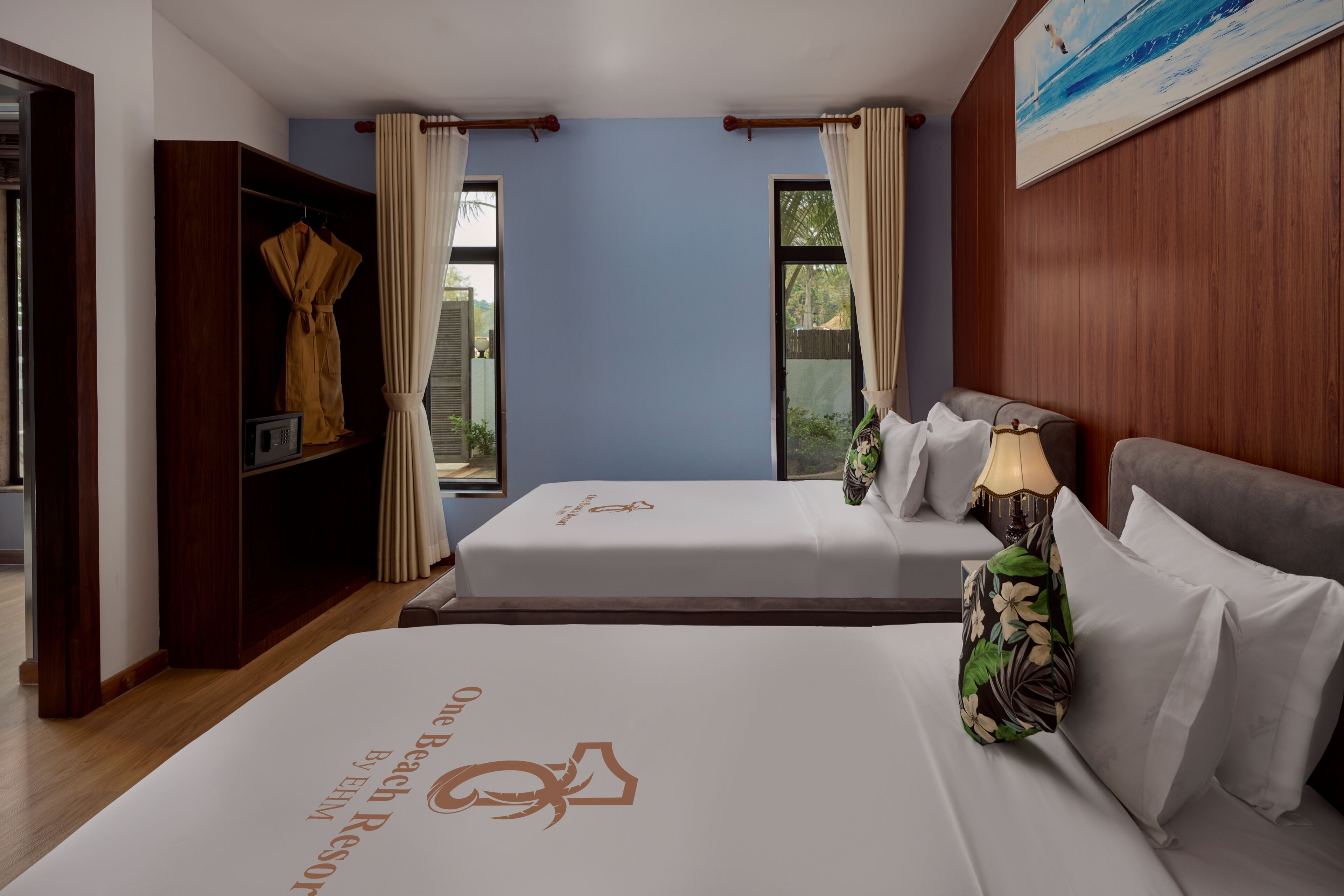 A hotel room with two beds, a wardrobe, a window with curtains, and a painting on the wall.