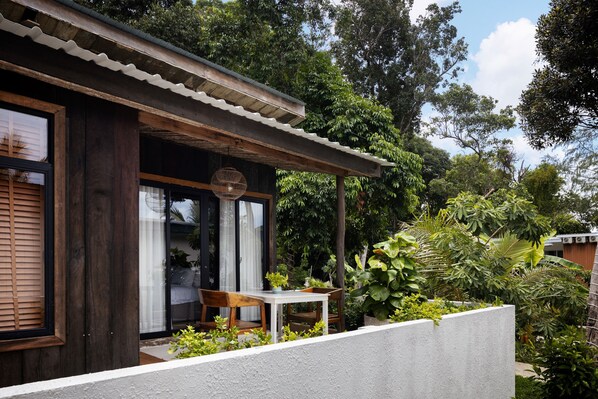 A wooden house with a balcony, surrounded by lush greenery.