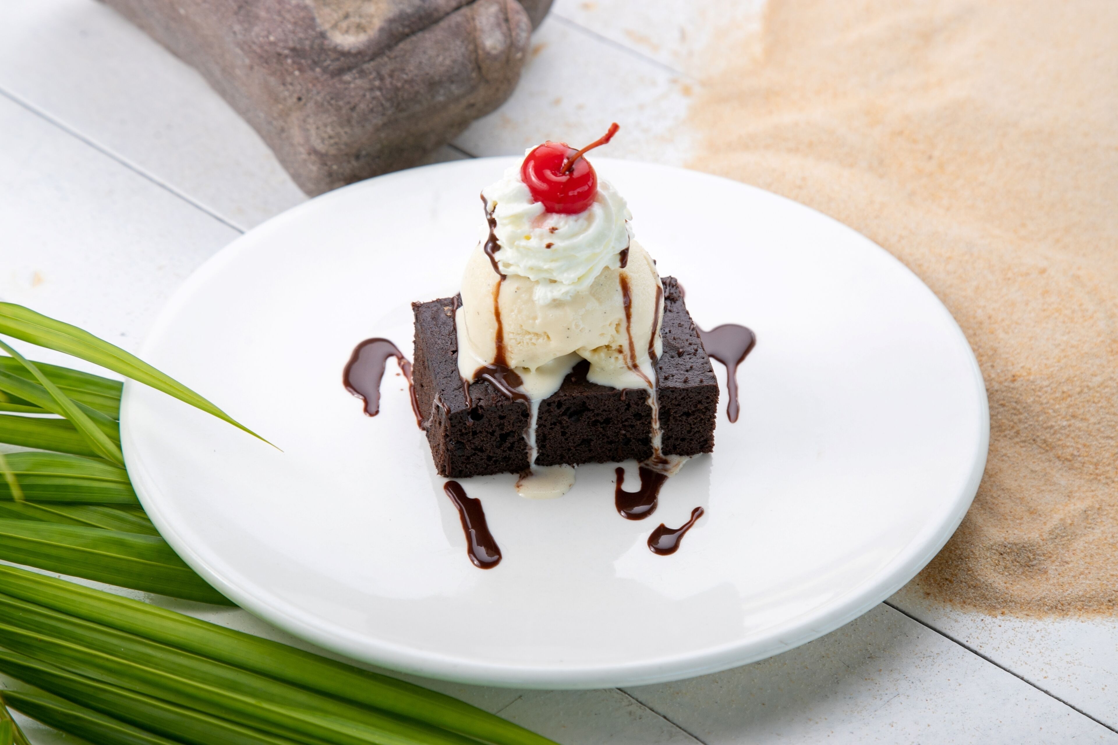 A dessert on a white plate with chocolate sauce and a cherry on top.