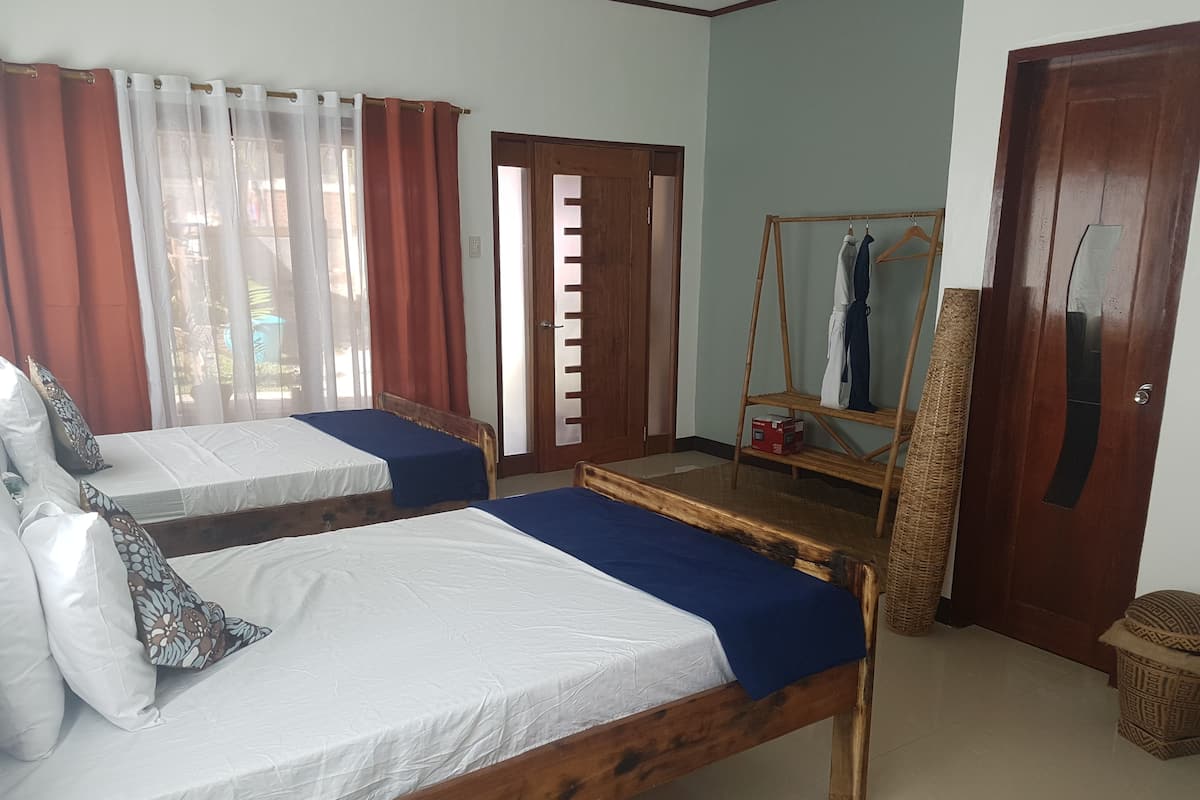 A room with two wooden beds, a wooden wardrobe, a mirror, and a clothes rack.