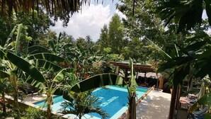 A swimming pool surrounded by lush tropical vegetation, with a pergola and lounge chairs nearby. - La Colonial Resort - Adults Only (El Nido)